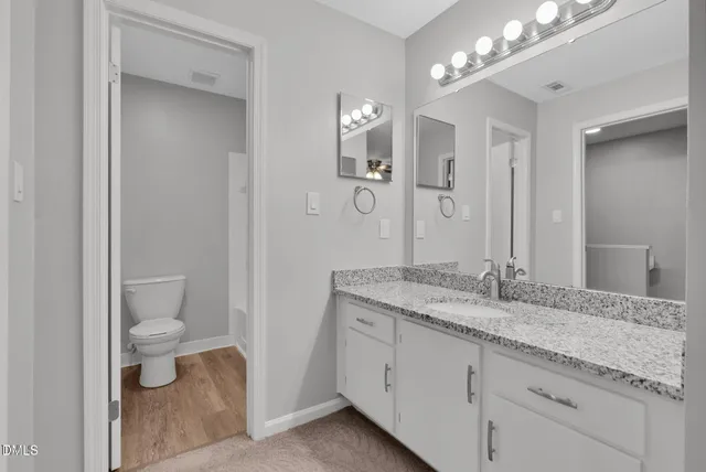 a bathroom with a granite countertop sink a toilet and a mirror