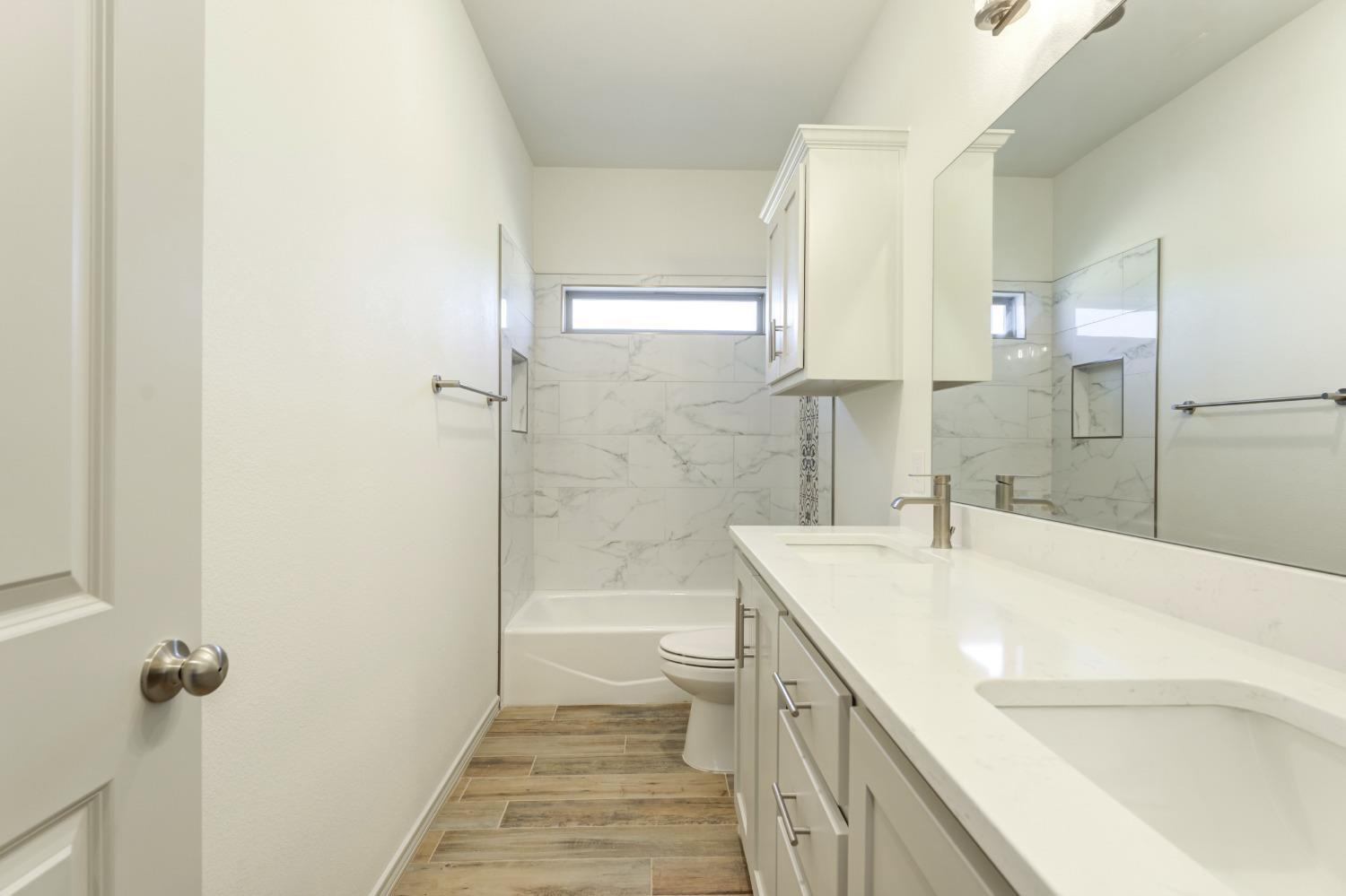 4608 140th Street Lubbock, TX 79424 - Photo 30 of 49 a bathroom with a granite countertop sink a toilet a mirror and shower