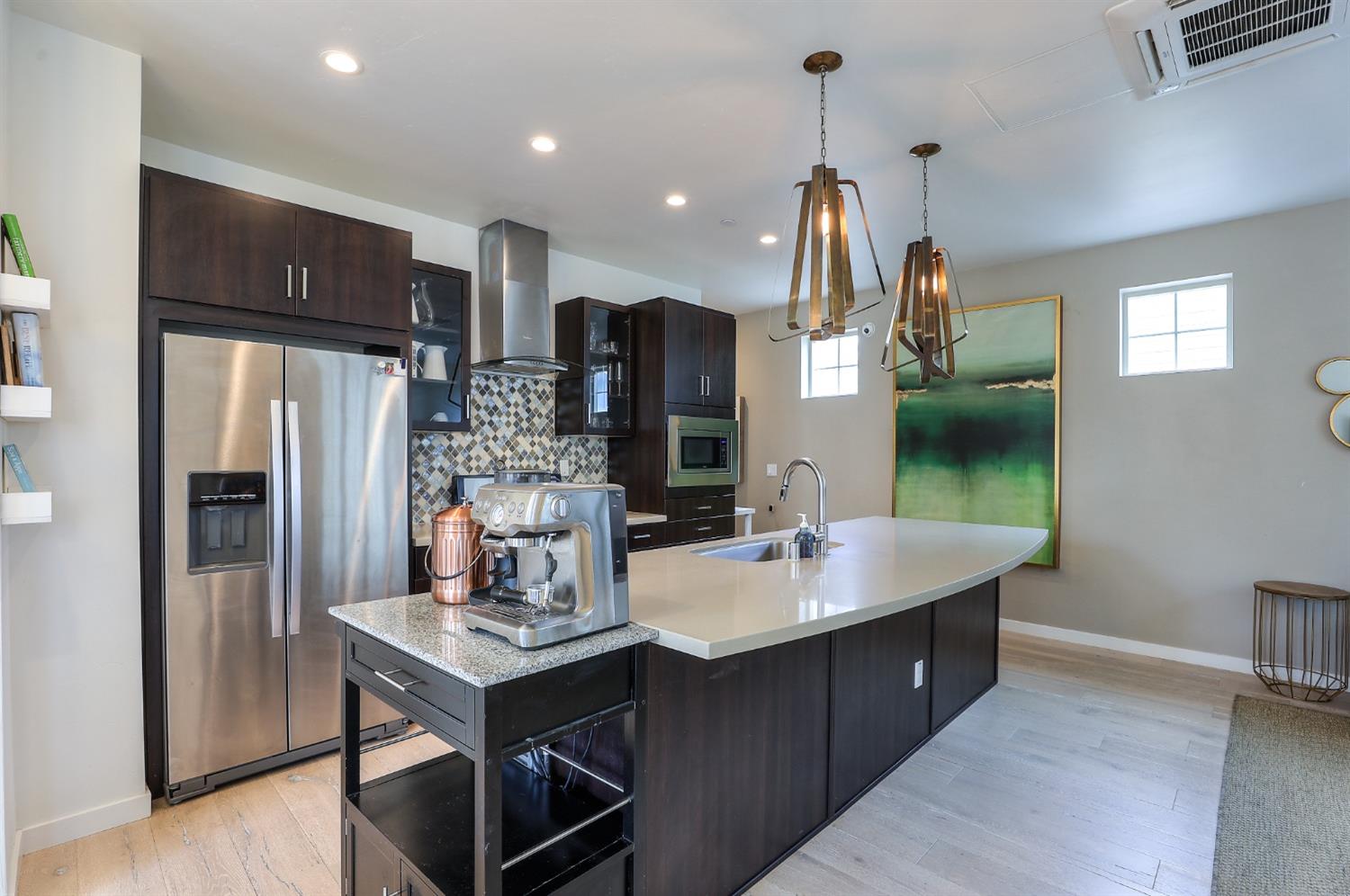 a kitchen with stainless steel appliances kitchen island granite countertop a sink refrigerator and cabinets