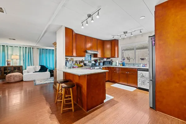 a large kitchen with kitchen island granite countertop wooden floors and a view of living room