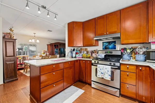 a kitchen with stainless steel appliances granite countertop a stove top oven a sink dishwasher and cabinets with wooden floor