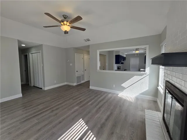 an empty room with wooden floor a ceiling fan and windows