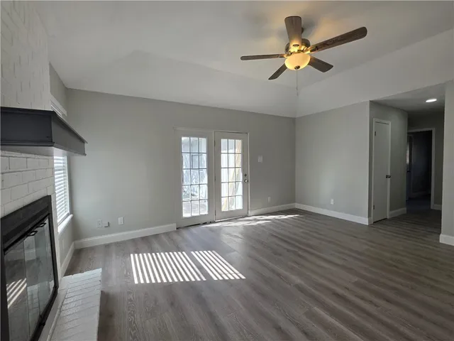 an empty room with wooden floor a ceiling fan and a fireplace