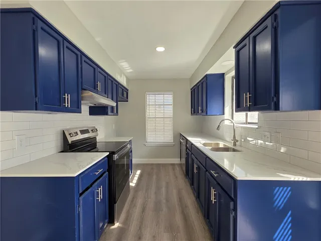 a kitchen with a sink stove top oven and wooden cabinets
