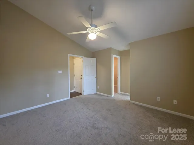a view of an empty room with a ceiling fan and window