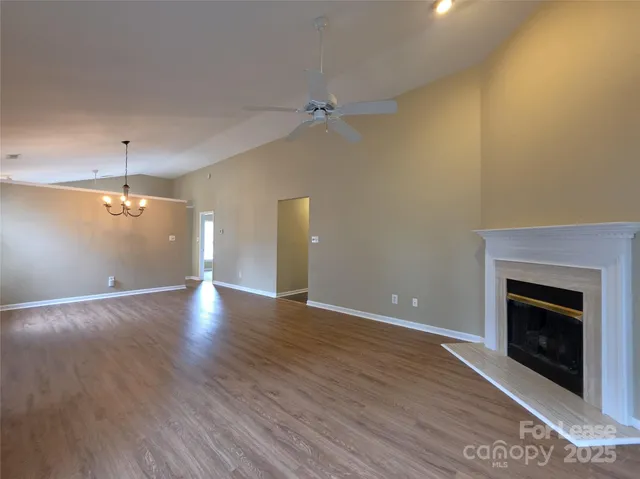 an empty room with wooden floor fireplace and windows