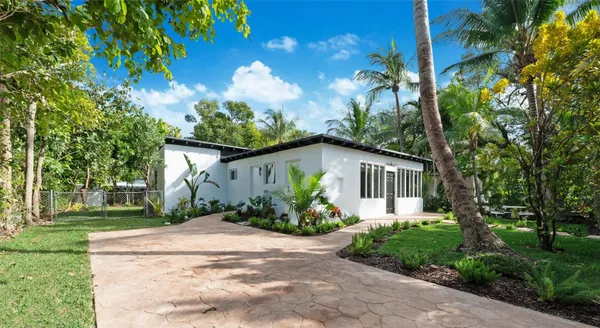 a front view of a house with a yard and potted plants