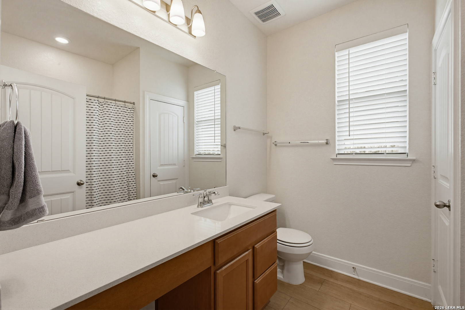 7829 Big Wind Way Austin, TX 78724 - Photo 19 of 26 a bathroom with a granite countertop sink a toilet and a large mirror