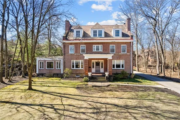 a view of a brick house with many windows next to a yard