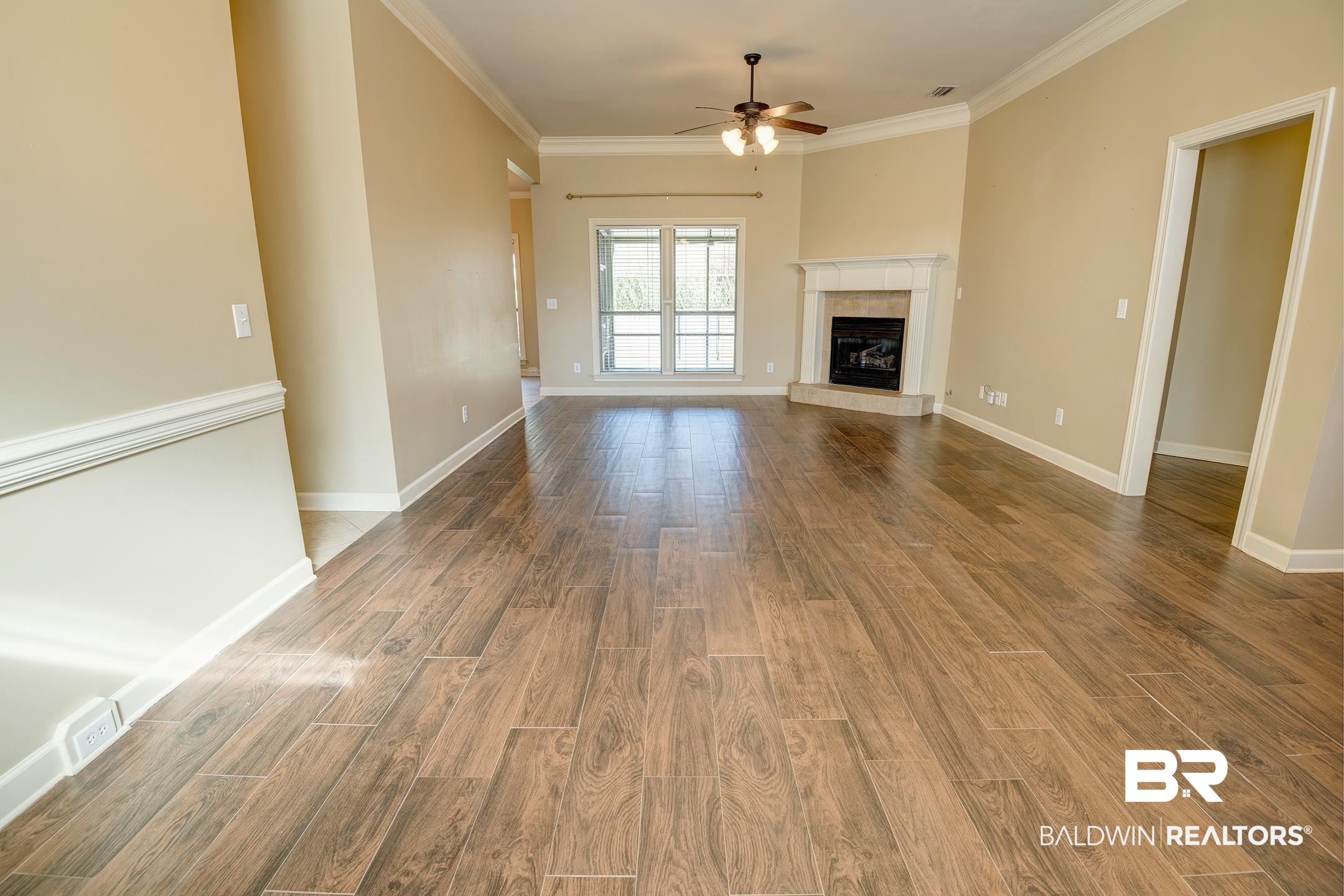 9421 Collier Loop Daphne, AL 36526 - Photo 8 of 31 Unfurnished living room with ornamental molding, wood finished floors, a fireplace, and a ceiling fan
