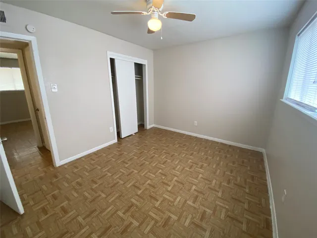 an empty room with windows and fan