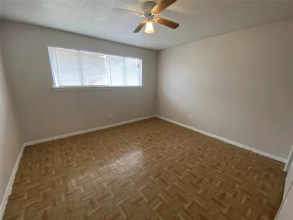 an empty room with a chandelier fan and windows