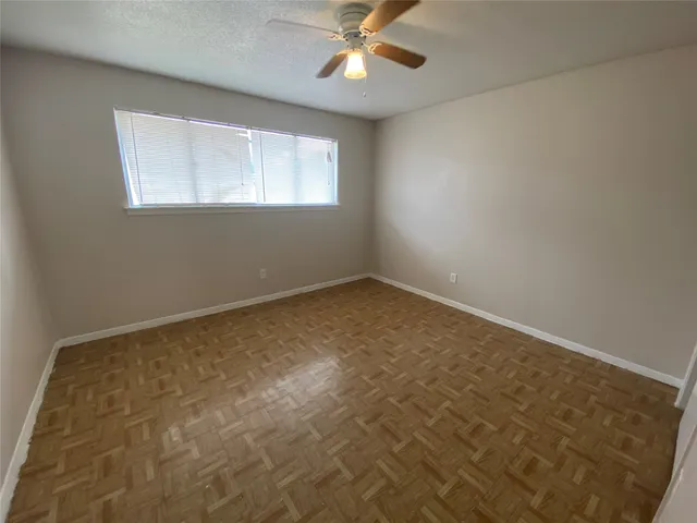 an empty room with a chandelier fan and windows