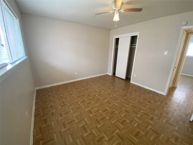 an empty room with a chandelier fan and windows