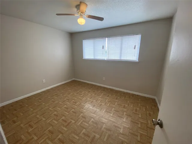 an empty room with a chandelier fan and windows