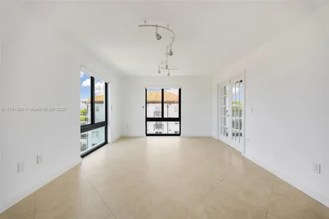 an empty room with windows and ceiling fan