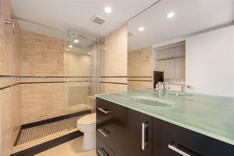 a bathroom with a sink a toilet a mirror and shower