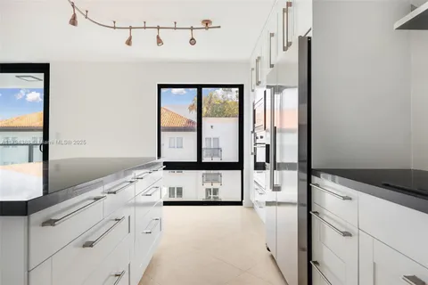 a kitchen with a refrigerator a stove and white cabinets next to a window