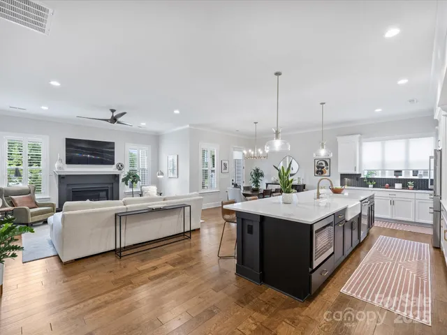 a large kitchen with stainless steel appliances a stove a sink dishwasher and a living room with kitchen island