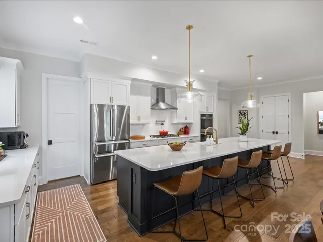 a kitchen with stainless steel appliances a dining table chairs stove and refrigerator