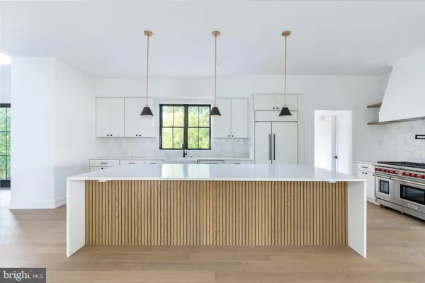 a large kitchen with kitchen island a stove a sink a center island and windows