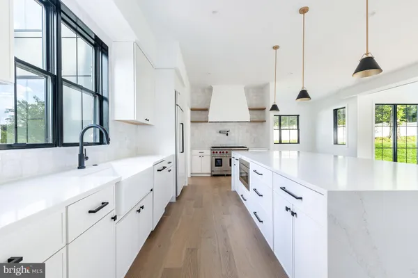 a large white kitchen with stainless steel appliances sink and a large window