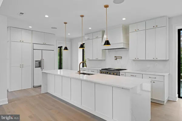 a kitchen with stainless steel appliances granite countertop a sink a stove a refrigerator and white cabinets