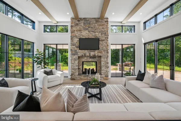 a living room with furniture fireplace and large windows