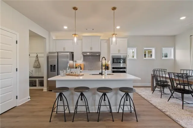 a kitchen with stainless steel appliances a dining table chairs stove refrigerator and wooden floor