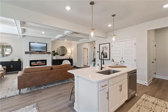 a kitchen with stainless steel appliances granite countertop a stove a sink a microwave a refrigerator and white cabinets with wooden floor