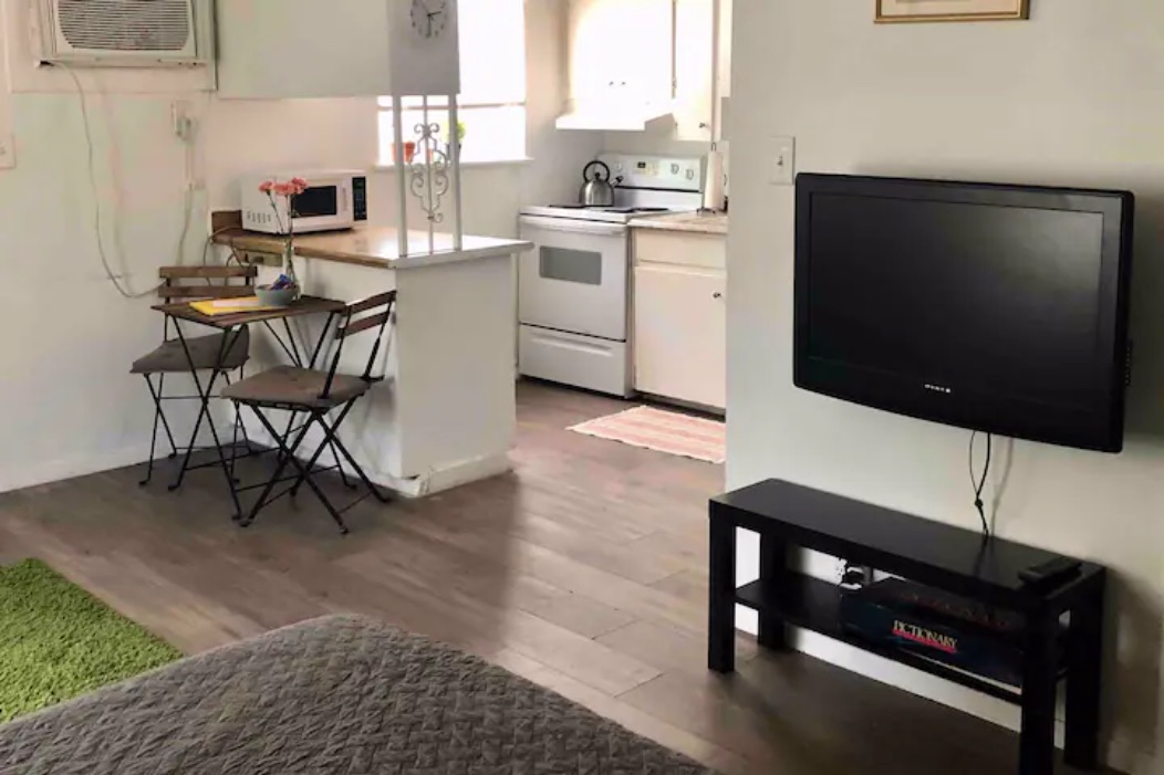 5909 Bolm Road, Unit 2 Austin, TX 78721 - Photo 4 of 10 Kitchen featuring white appliances, light countertops, white cabinets, dark wood-style floors, and a wall unit AC