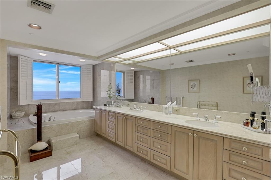 10 Seagate Drive, Unit 6S Naples, FL 34103 - Photo 21 of 34 a bathroom with a granite countertop sink mirror and bathtub