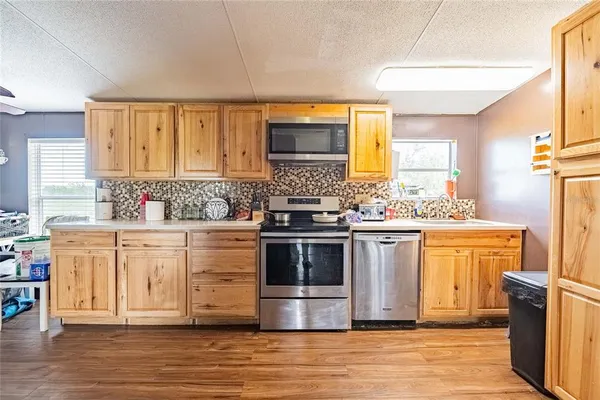 a kitchen with stainless steel appliances a stove top oven a sink dishwasher and a refrigerator with wooden floor