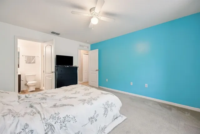 a bedroom with a bed and a lamp on dresser