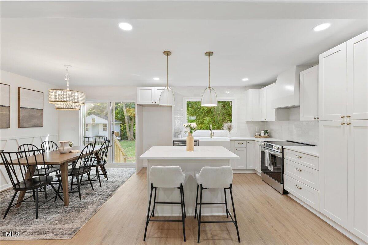217 Brandon Court Raleigh, NC 27609 - Photo 8 of 30 a kitchen with stainless steel appliances kitchen island granite countertop a stove a sink a dining table and chairs with wooden floor
