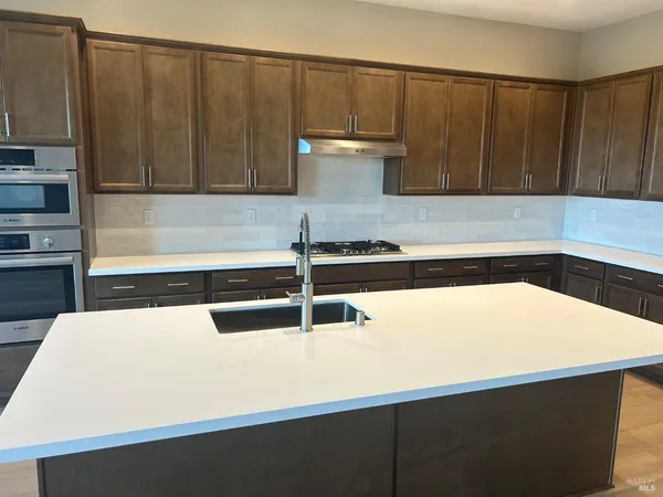 a kitchen with stainless steel appliances kitchen island wooden cabinets and a stove top oven