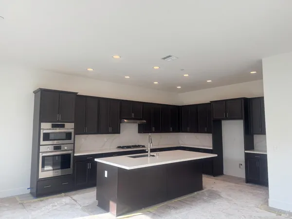 a large kitchen with stainless steel appliances granite countertop a large counter top a stove and a wooden floors