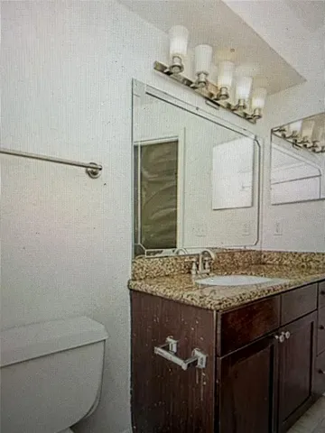 a bathroom with a granite countertop sink a toilet and mirror