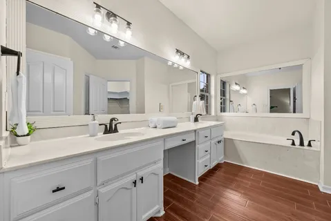 a spacious bathroom with a granite countertop sink mirror and bathtub