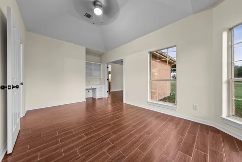 an empty room with wooden floor and windows