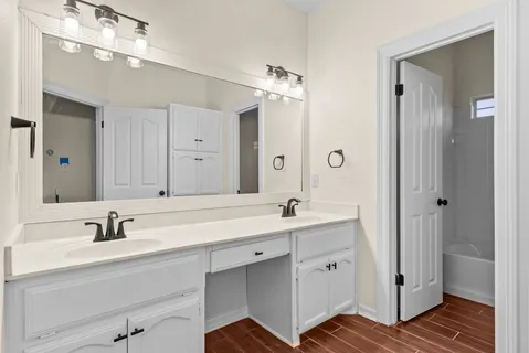 a bathroom with a double vanity sink a mirror and a bathtub