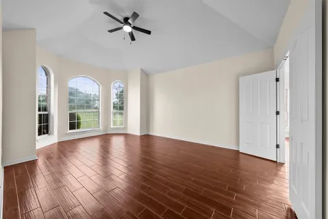 a view of empty room with wooden floor and fan