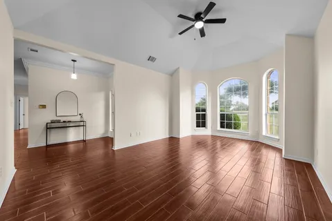 a view of empty room with wooden floor and fan