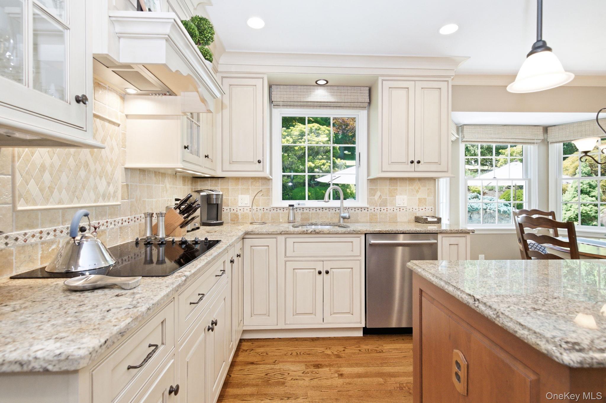 32 Bedell Road Katonah, NY 10536 - Photo 10 of 49 Glazed cabinetry, a tile backsplash, and an electric cooktop line the kitchen's work wall.