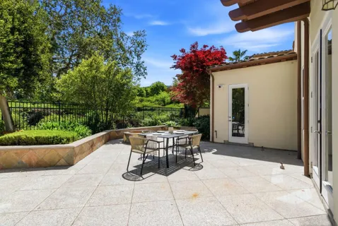 a view of backyard with seating space and trees in the background