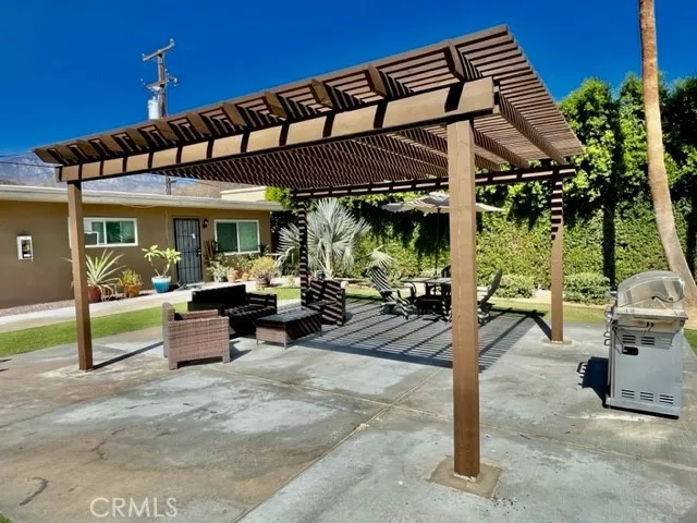 a view of a patio with table and chairs potted plants and a large tree