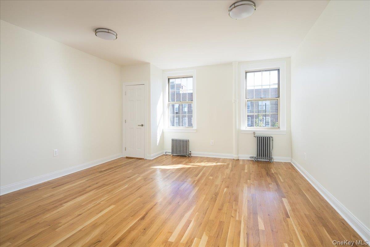 83-09 Talbot, Unit 6L Queens, NY 11415 - Photo 9 of 19 an empty room with wooden floor and windows