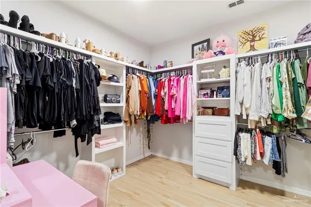 a view of walk in closet with clothes and shoes