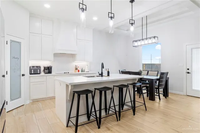 a open kitchen with stainless steel appliances granite countertop a dining table chairs and white cabinets next to a window