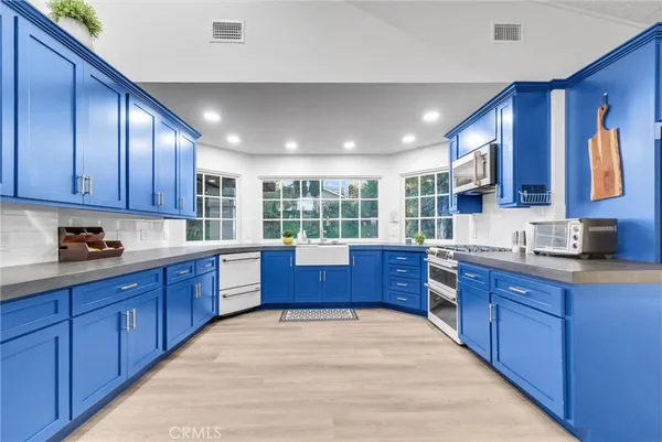 a kitchen with stainless steel appliances granite countertop wooden cabinets a stove a sink a window and wooden floors